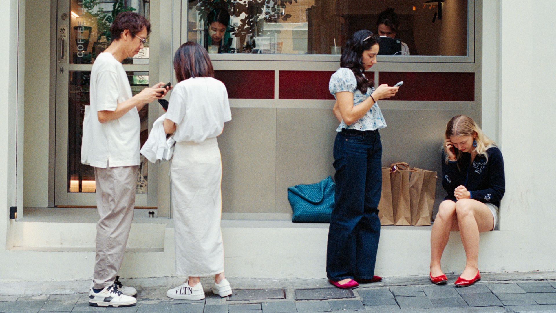 People outside cafe looking at phones