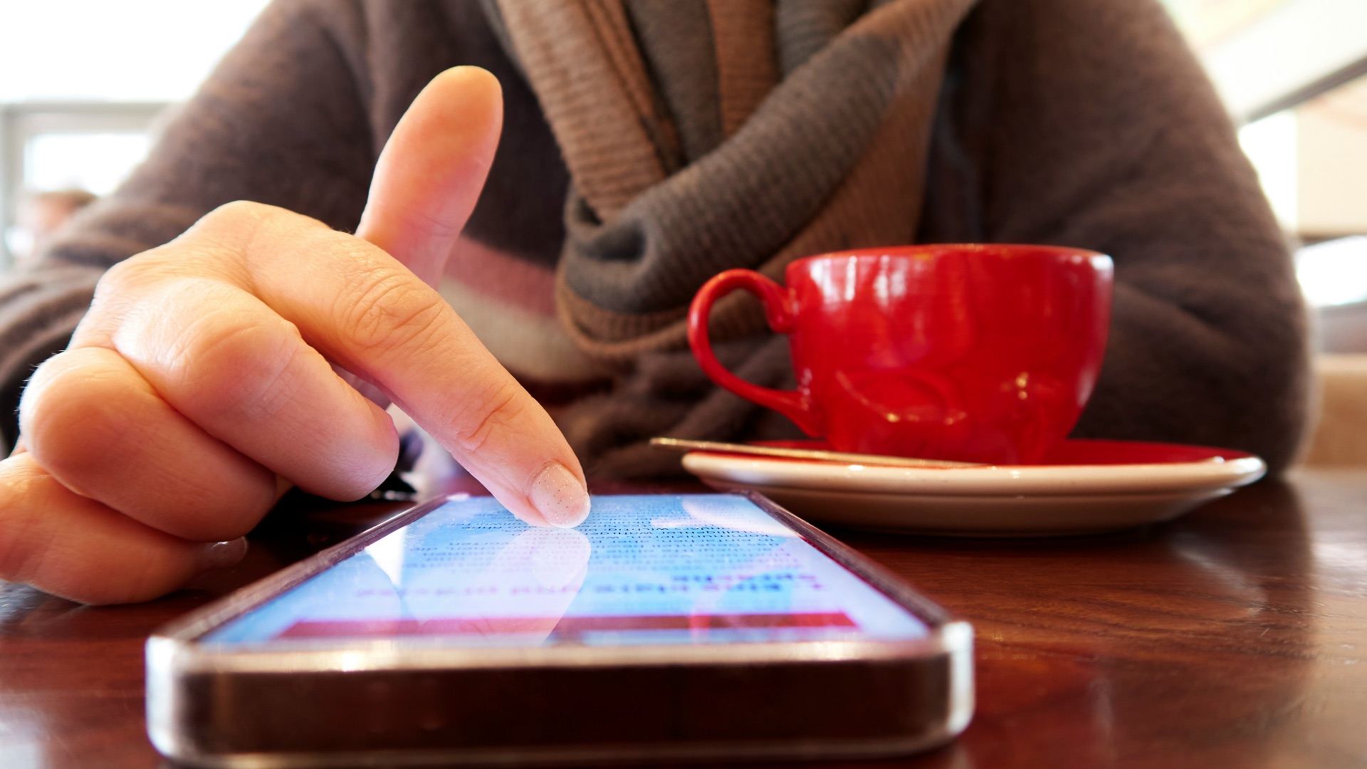 Person using a smartphone with a cup of coffee.