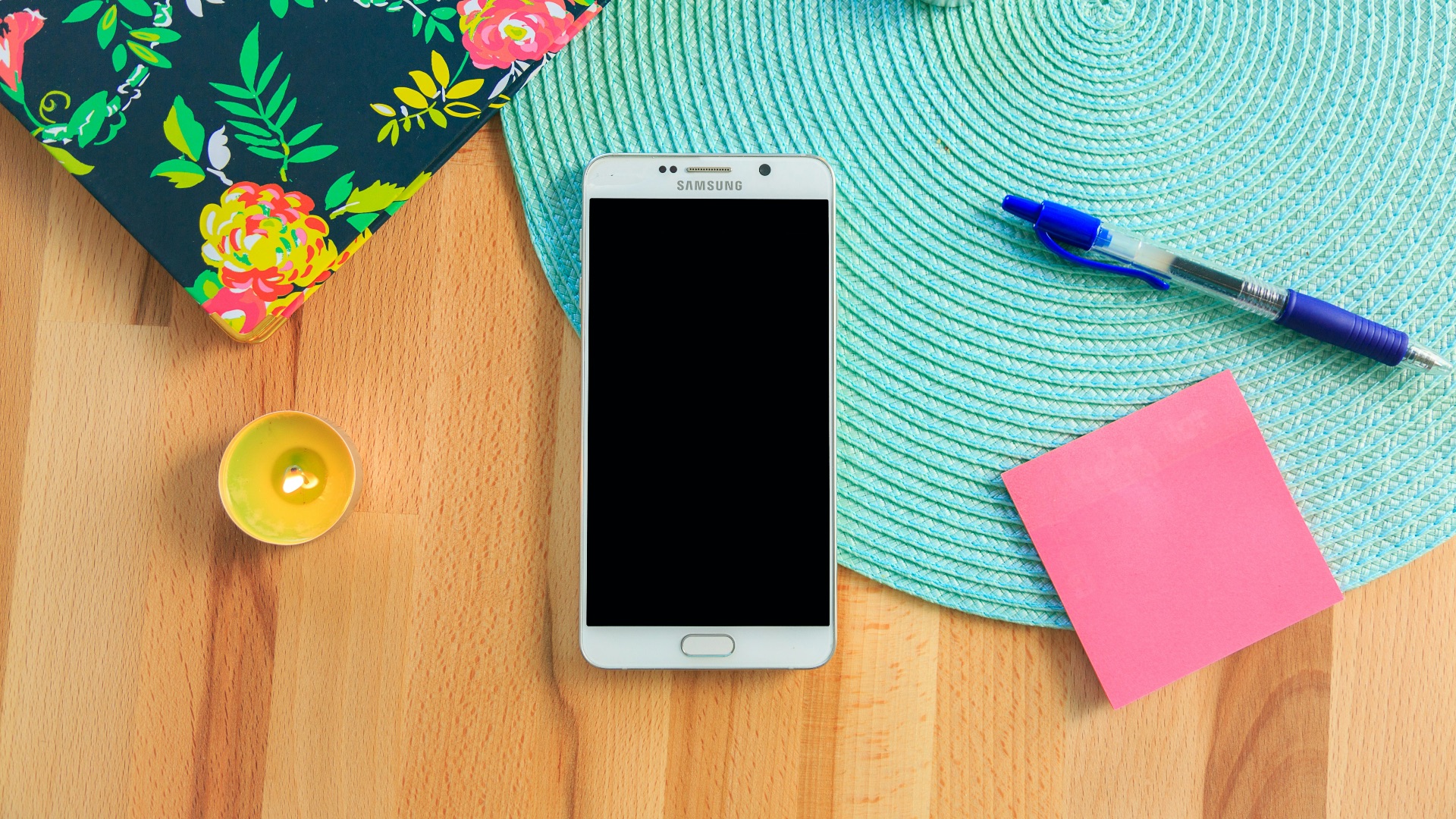 white Samsung Galaxy smartphone on top of blue place mat near blue click pen