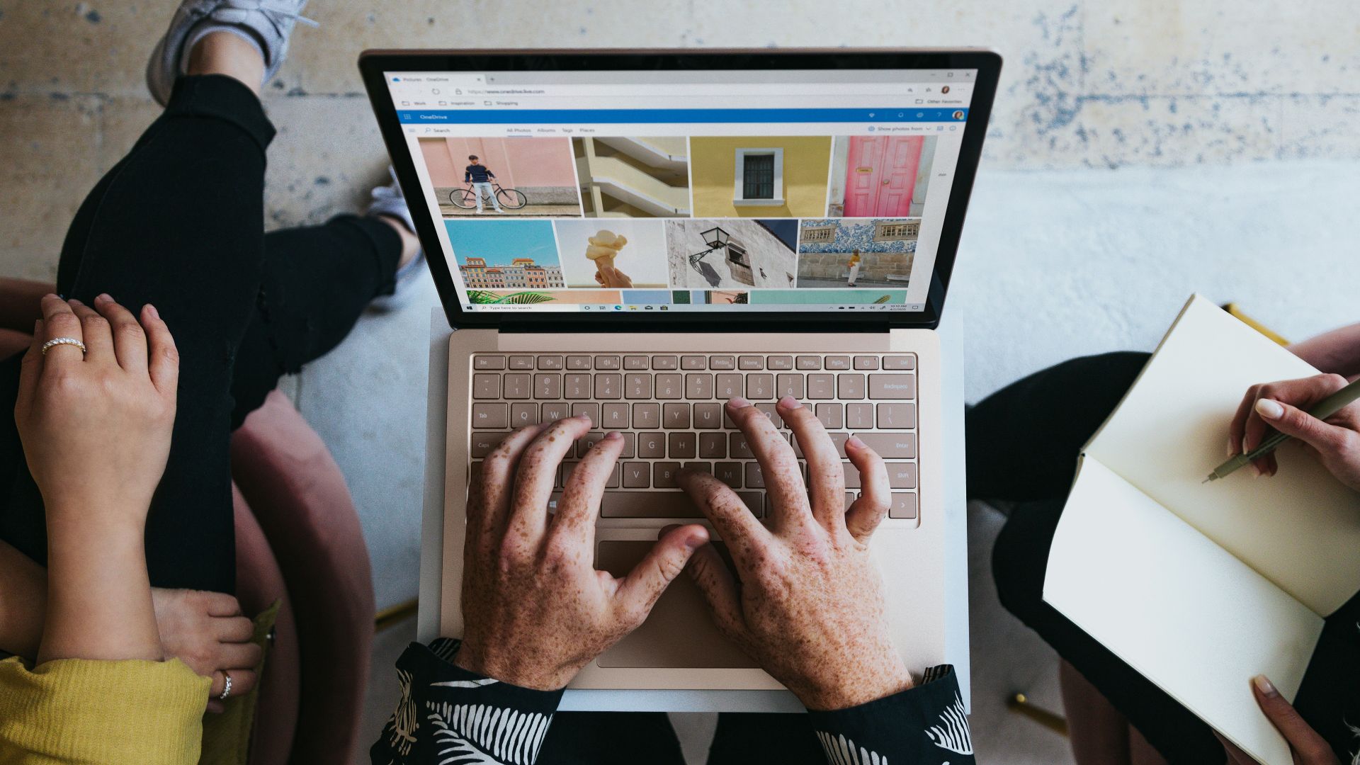 person using microsoft surface laptop on lap with two other people