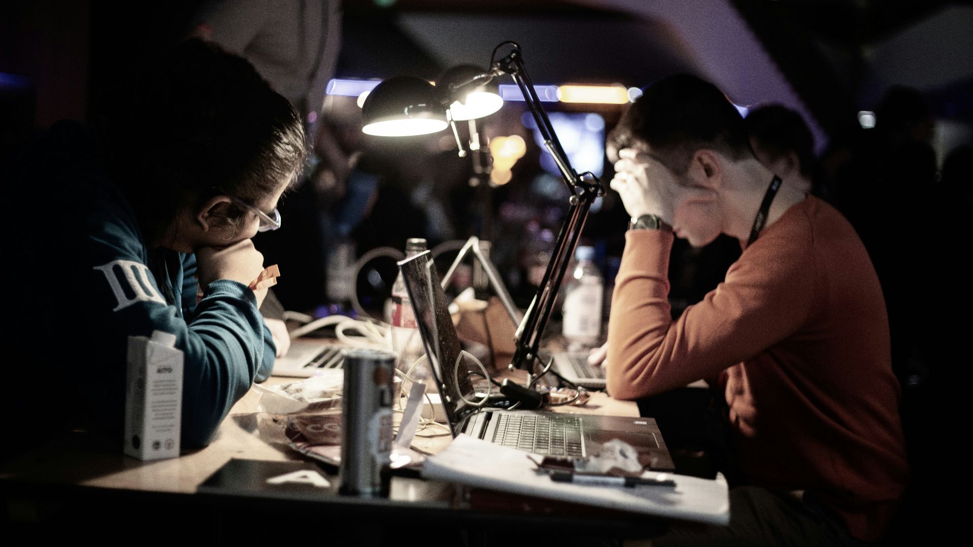 man in red long sleeve shirt sitting in front of table with laptop computer