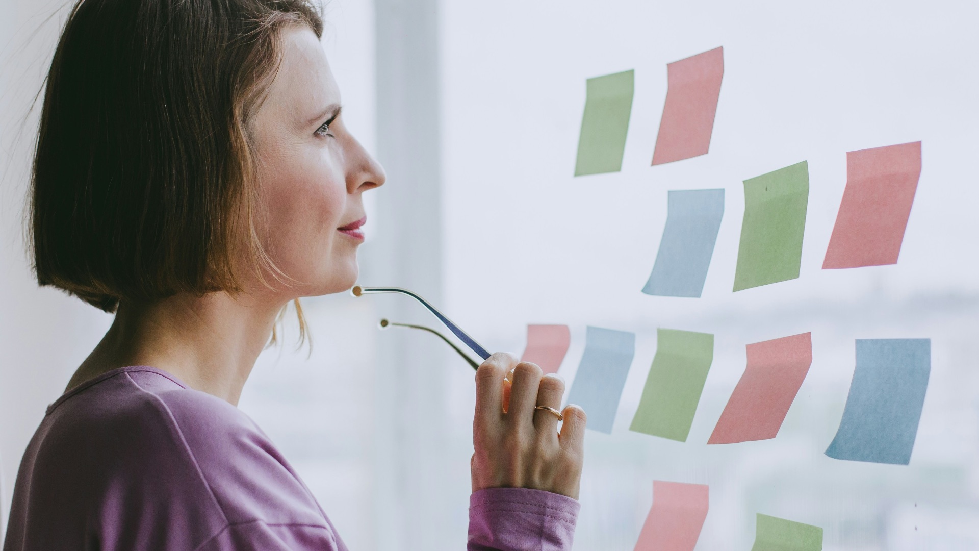 a woman looking out a window with sticky notes on it