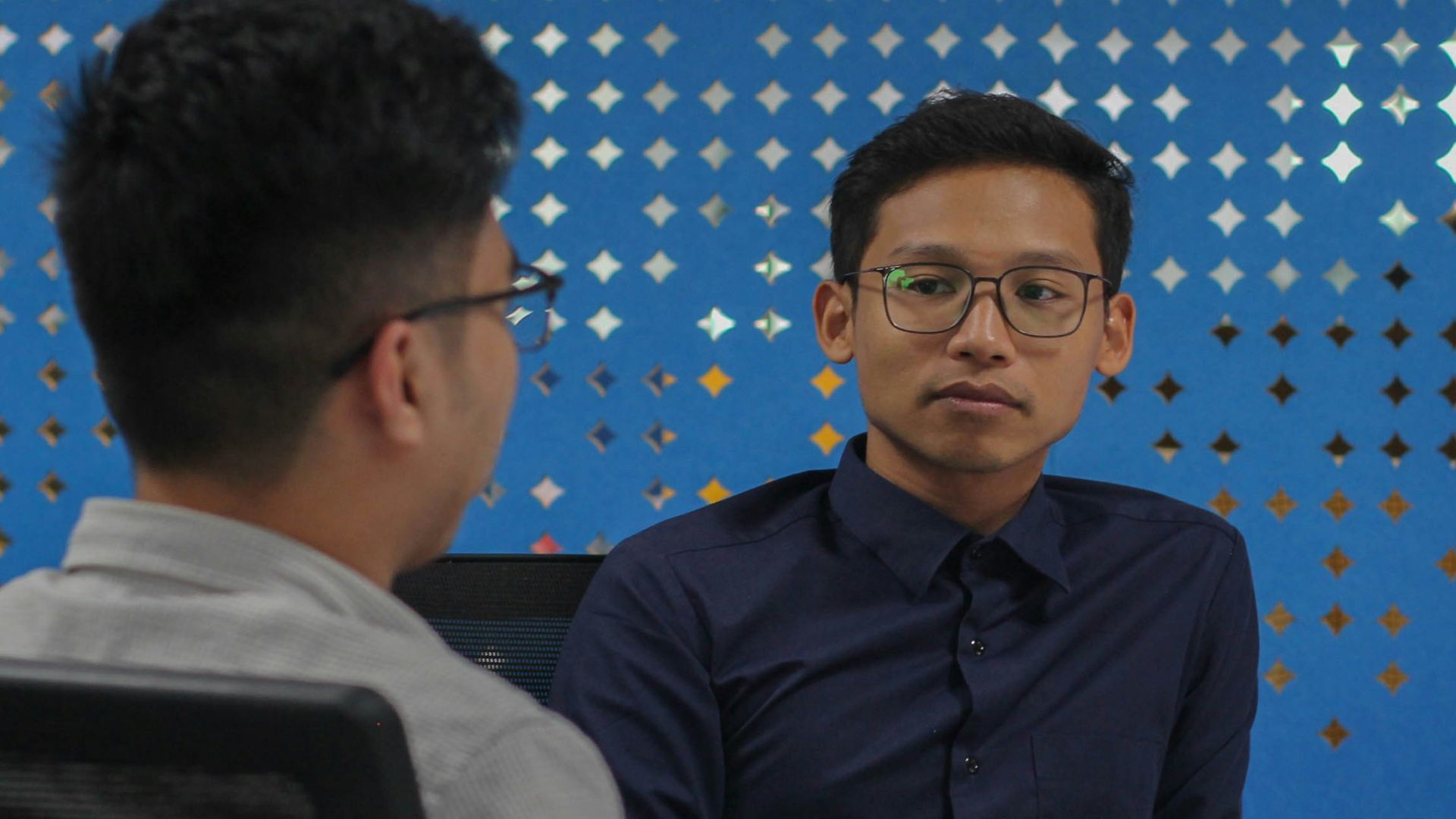 two men sitting at a table talking to each other