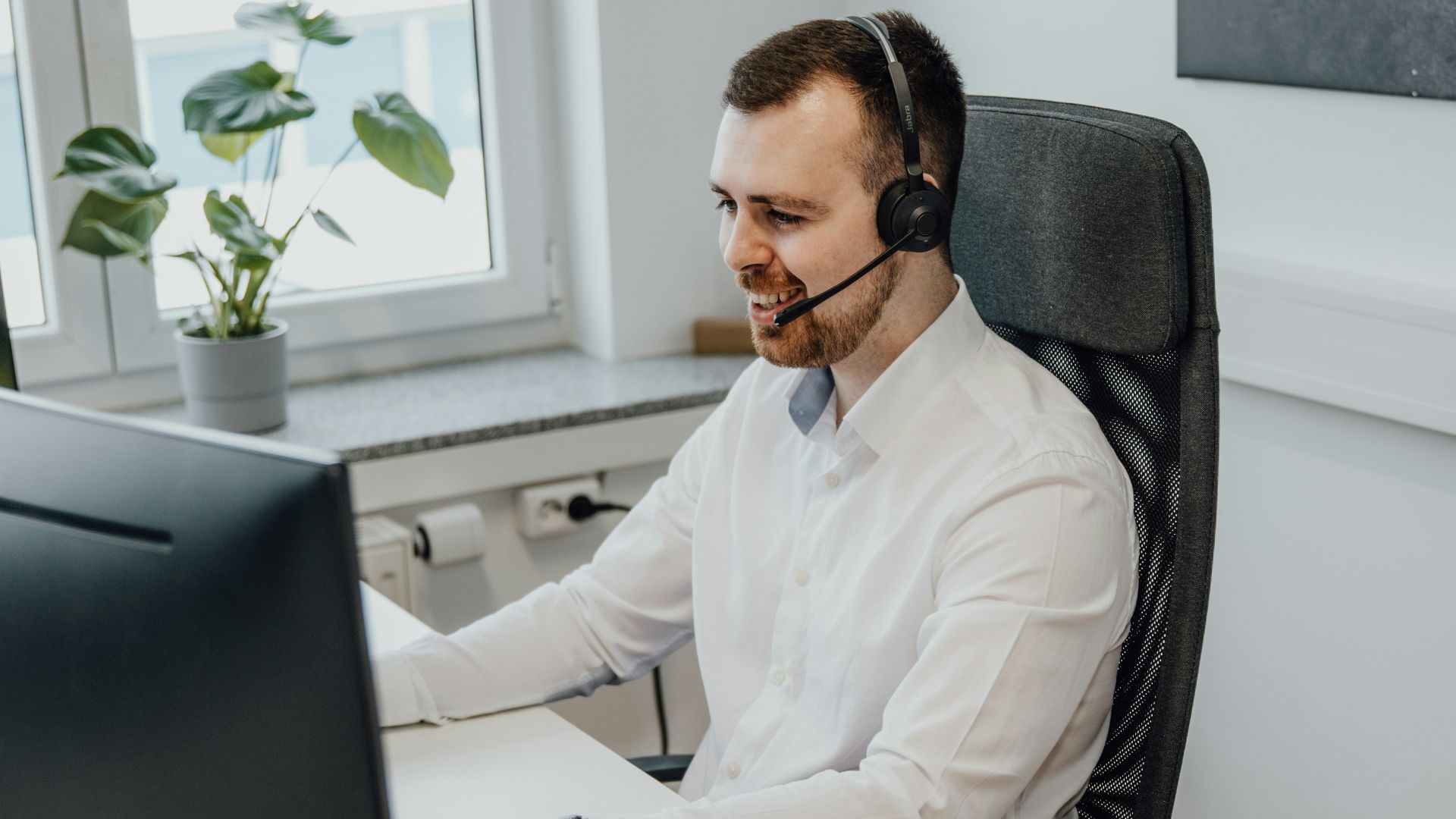 a man wearing a headset sitting in front of a computer