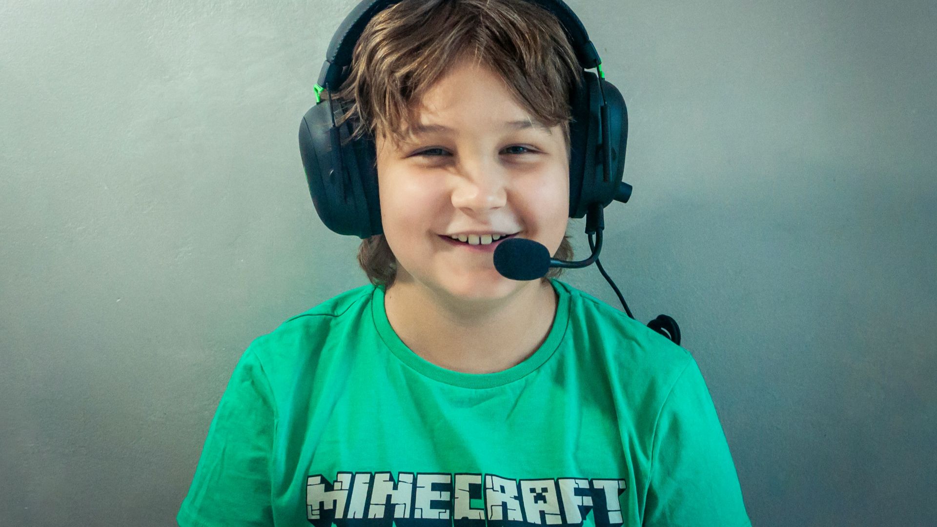 A young boy wearing headphones and a green shirt
