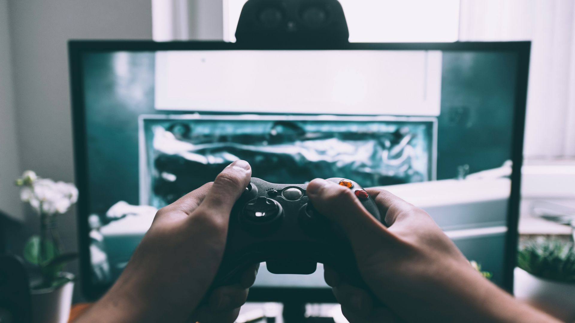 person holding game controller in-front of television