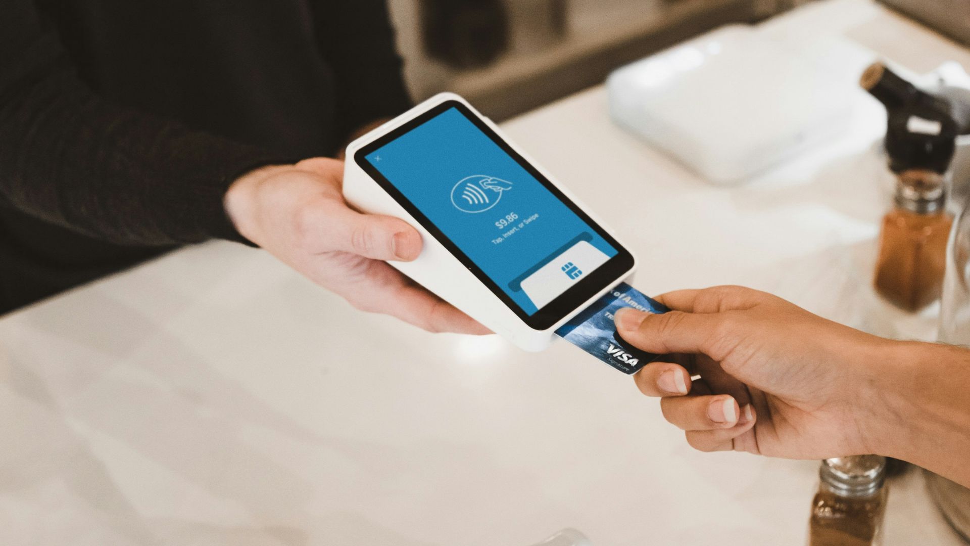 person putting magstripe card near black card terminal