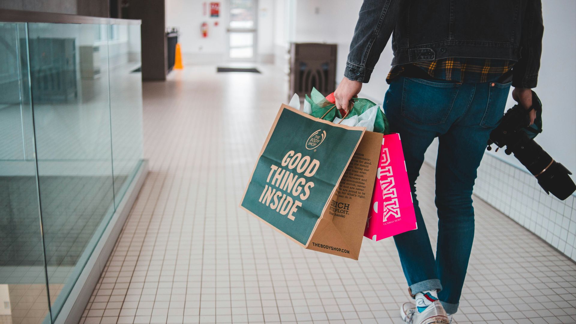 person walking while carrying a camera and paper bags
