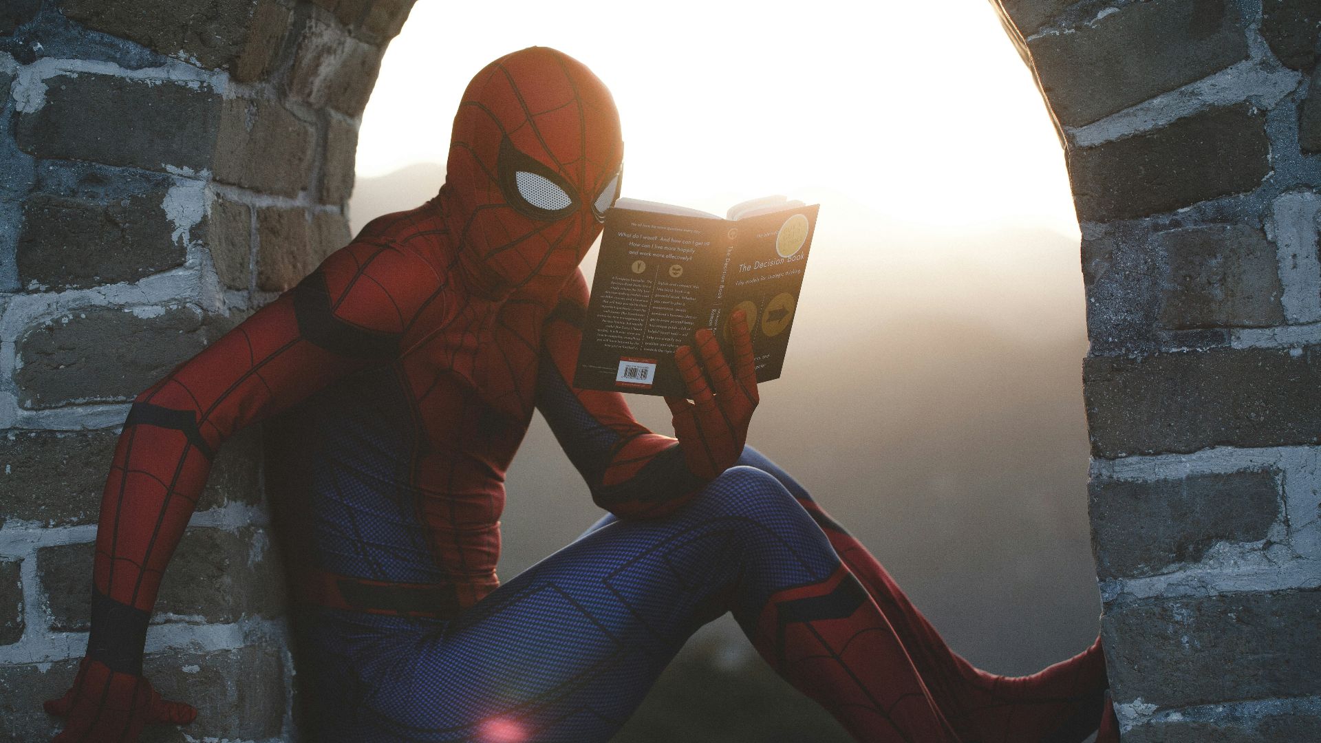 Spider-Man leaning on concrete brick while reading book