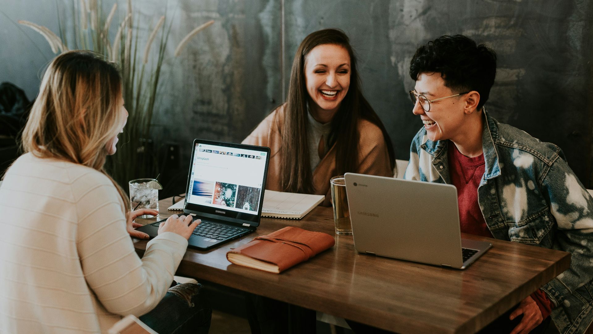 three people sitting in front of table laughing together