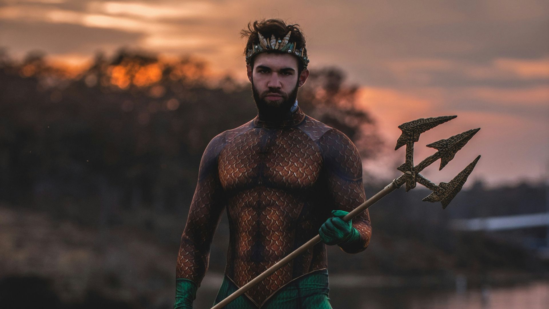 man wearing Poseidon costume standing on rock