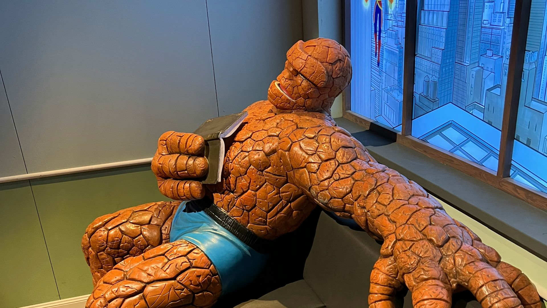 a large statue of a man sitting on a couch in front of a window