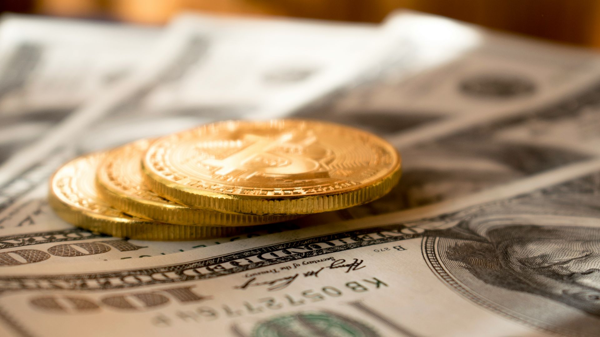 three round gold-colored coins on 100 US dollar banknotes