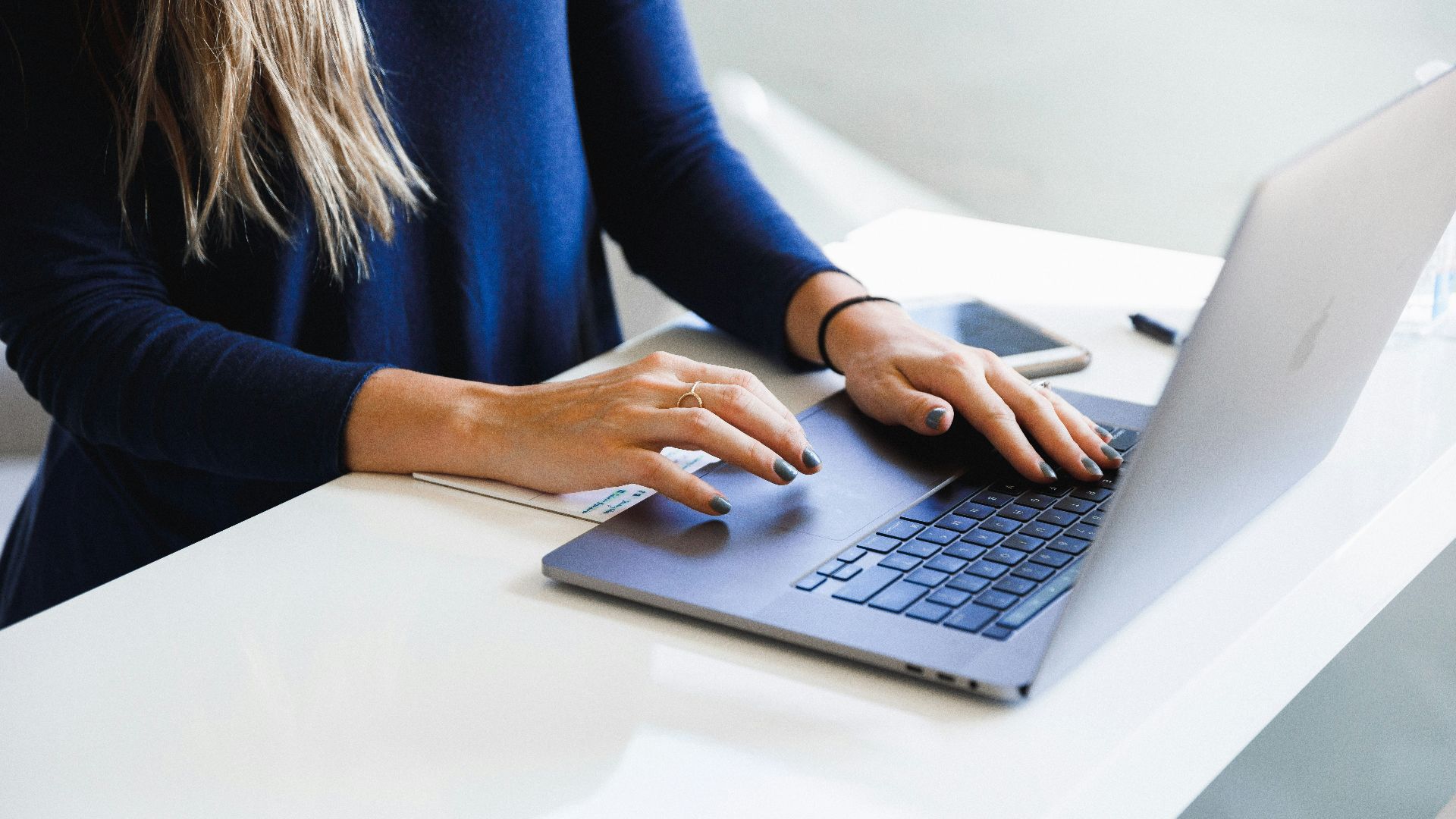woman in blue long sleeve shirt using macbook pro