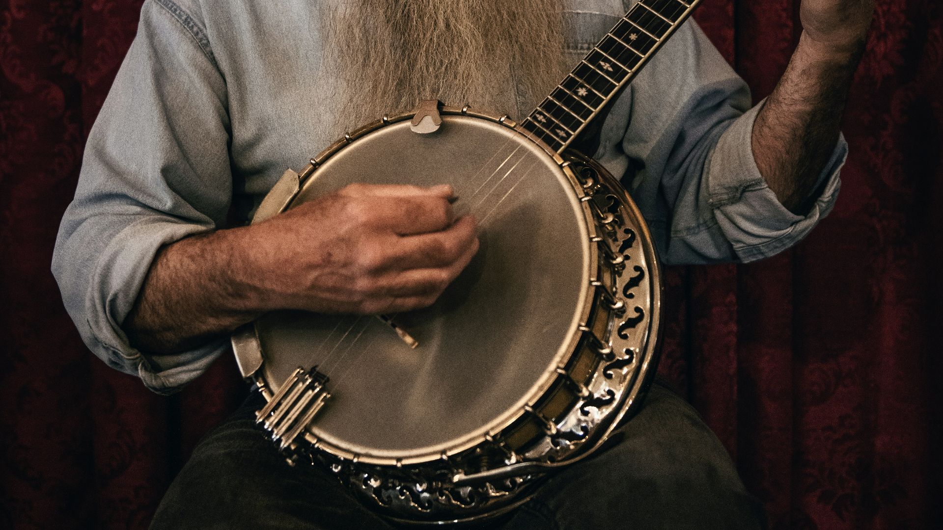 man in grey shirt playing acoustic guitar
