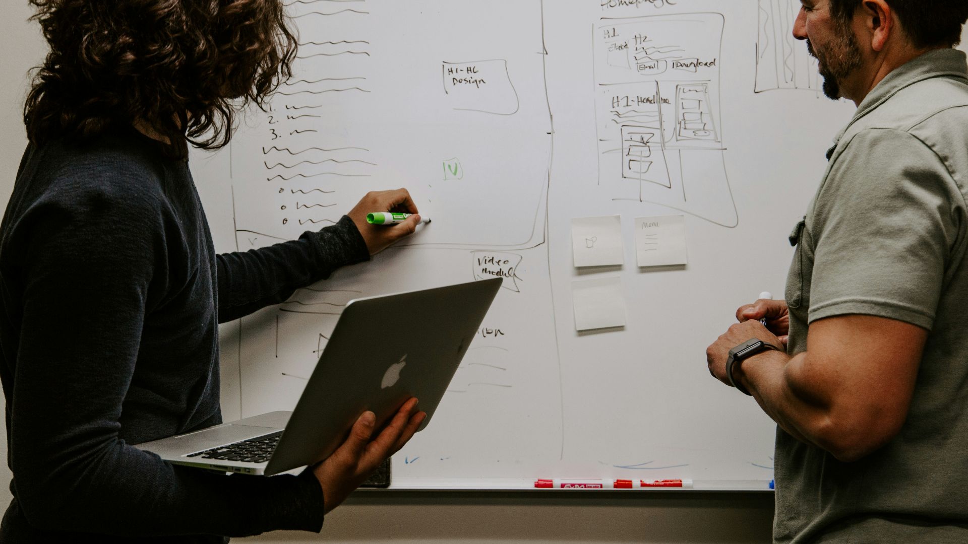 man wearing gray polo shirt beside dry-erase board