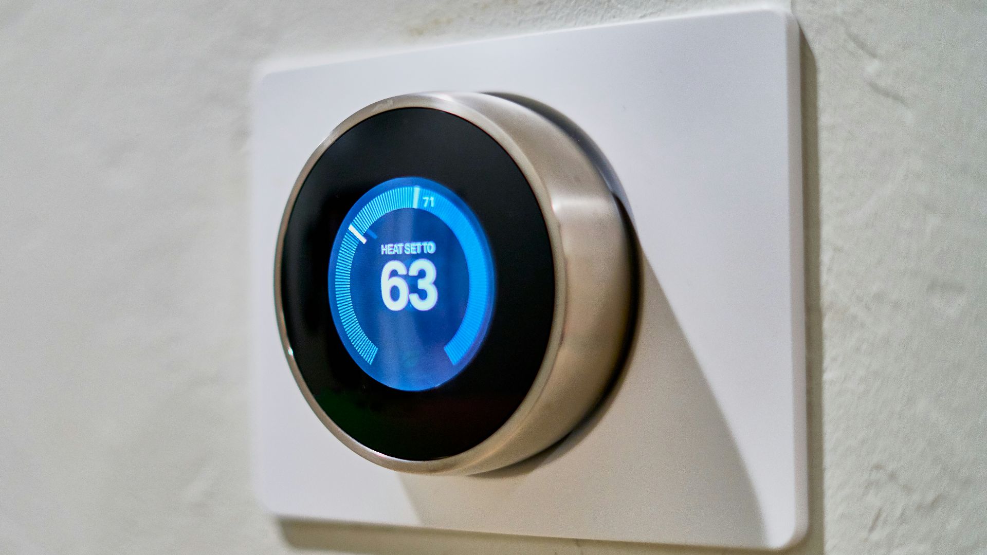 gray Nest thermostat displaying at 63