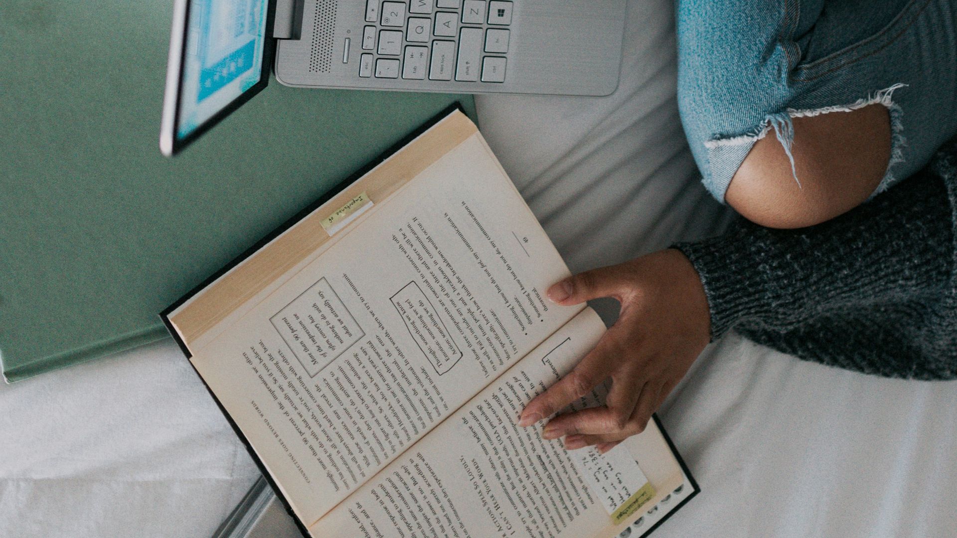 woman in blue long sleeve shirt and blue denim jeans sitting on bed using laptop