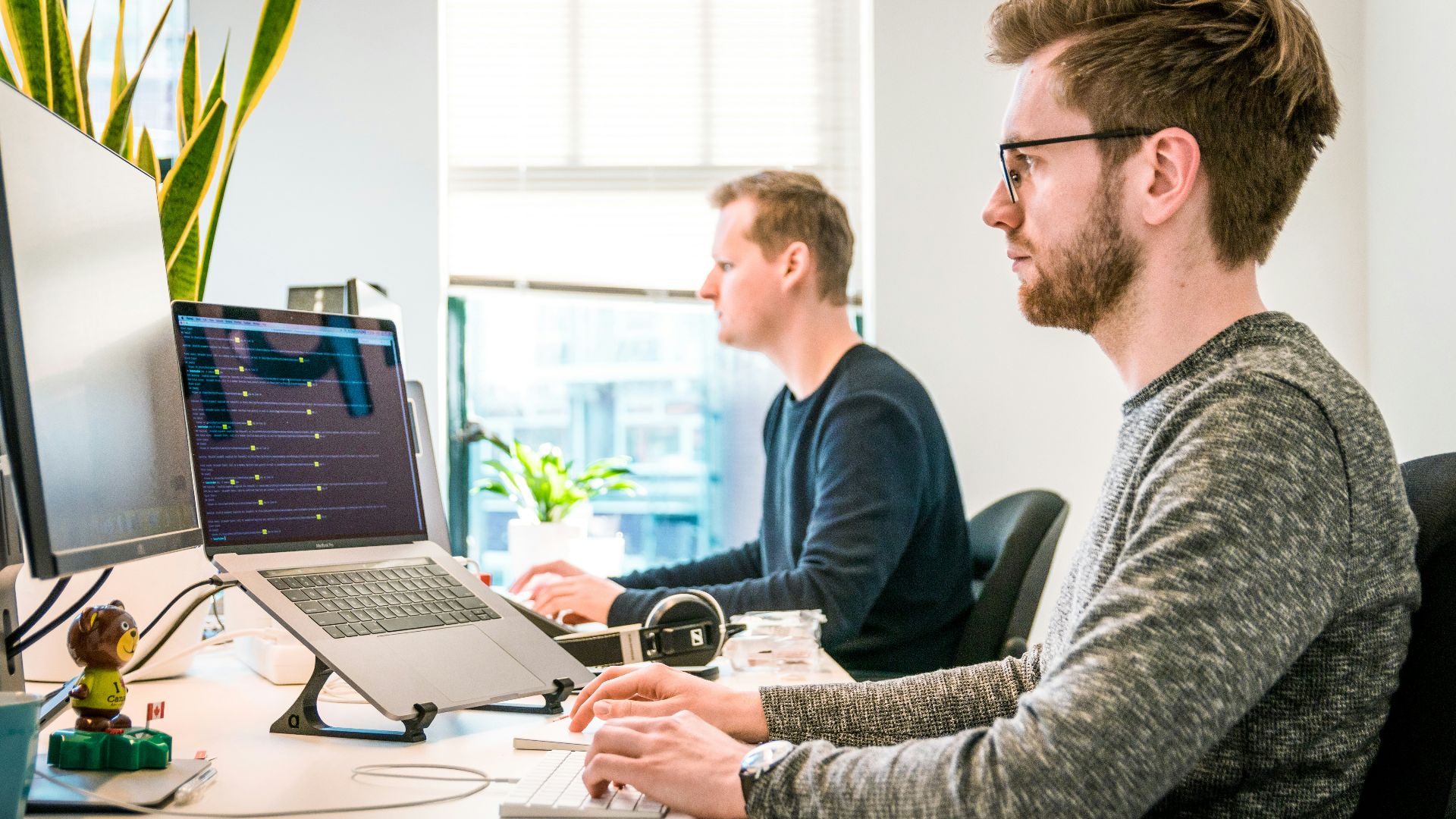 man sitting on chair wearing gray crew-neck long-sleeved shirt using Apple Magic Keyboard