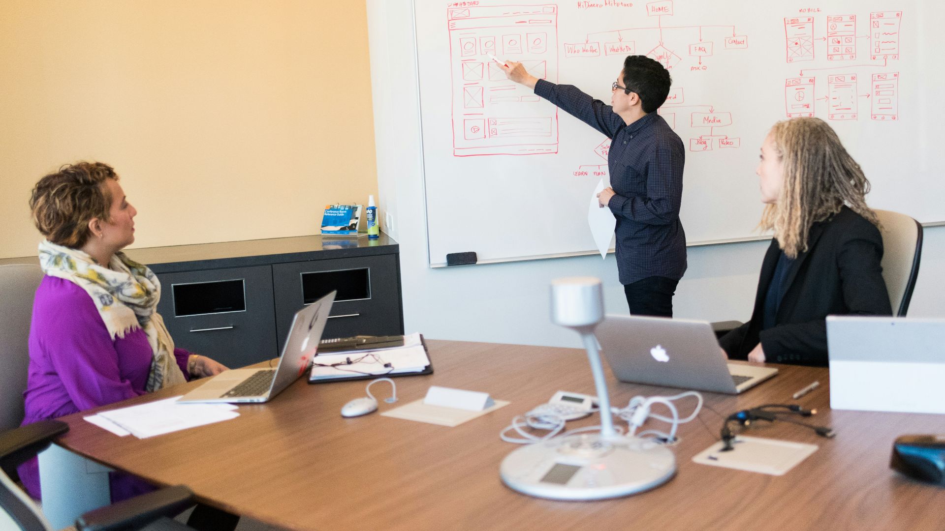 man in black dress shirt writing on dry-erase board