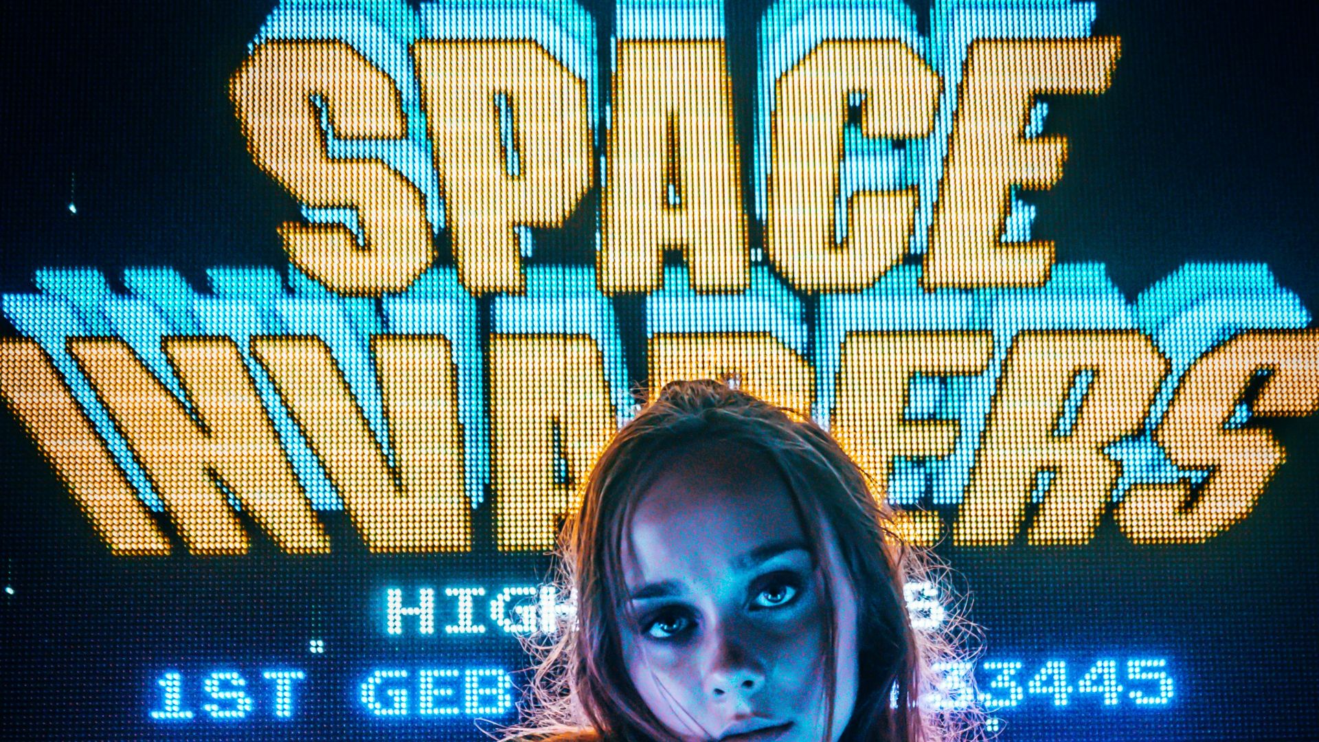 woman posing for photo in front of Space Invaders scoreboard