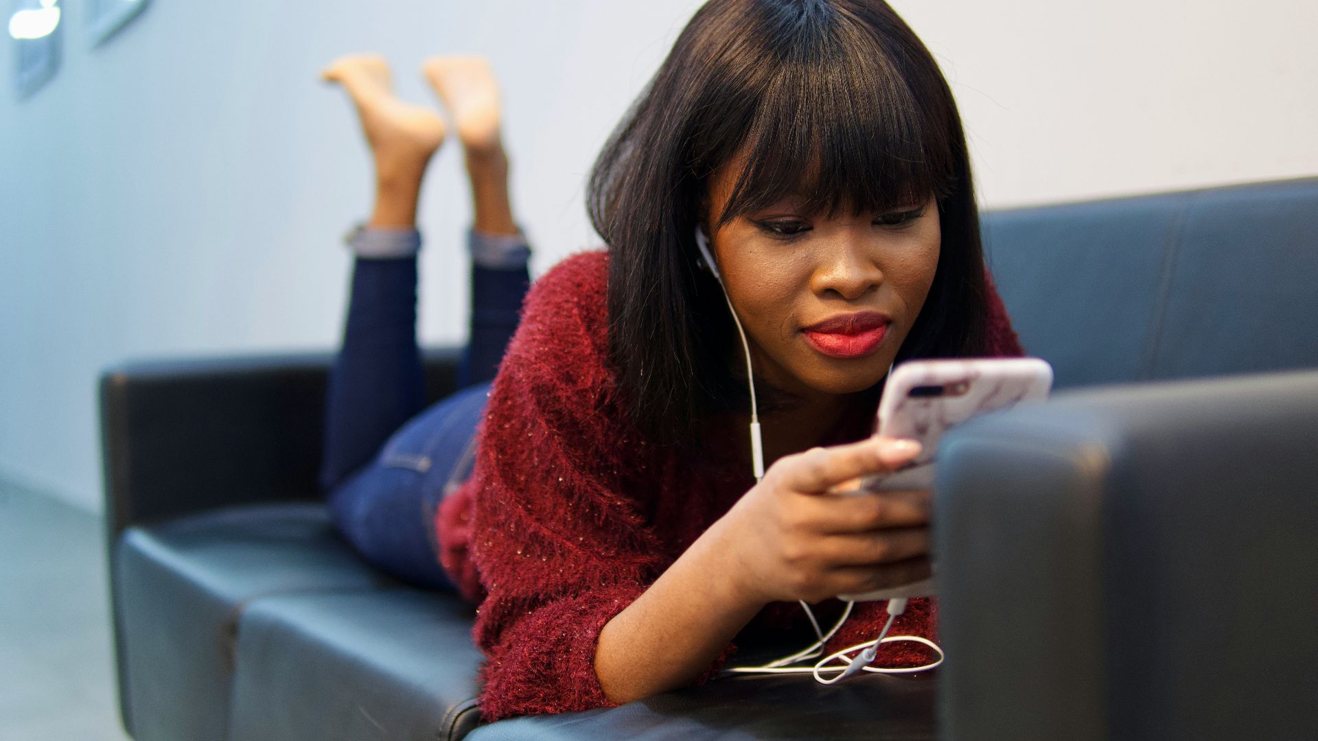 woman in blue sweater using white earbuds