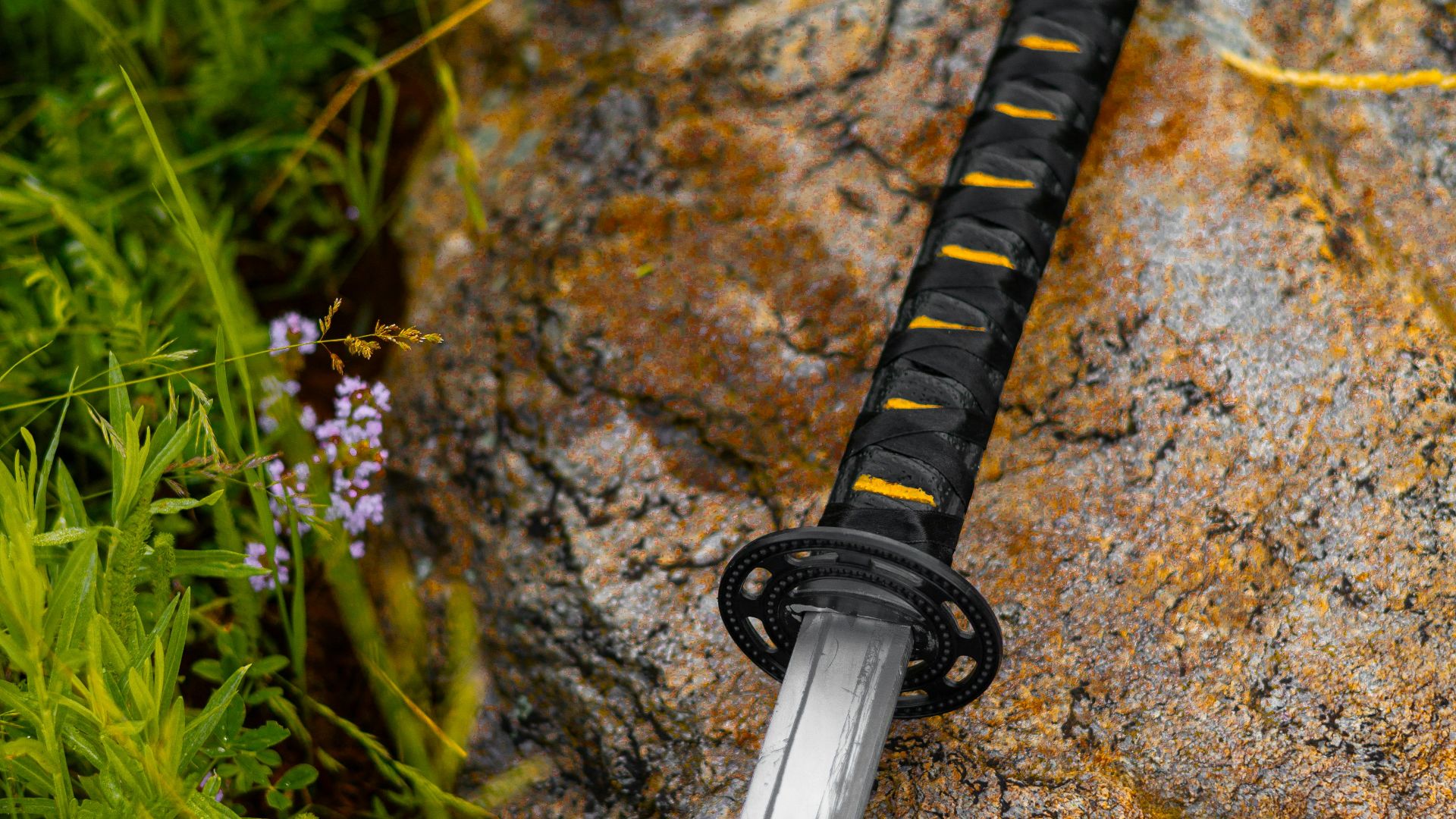 a sword laying on a rock in the grass