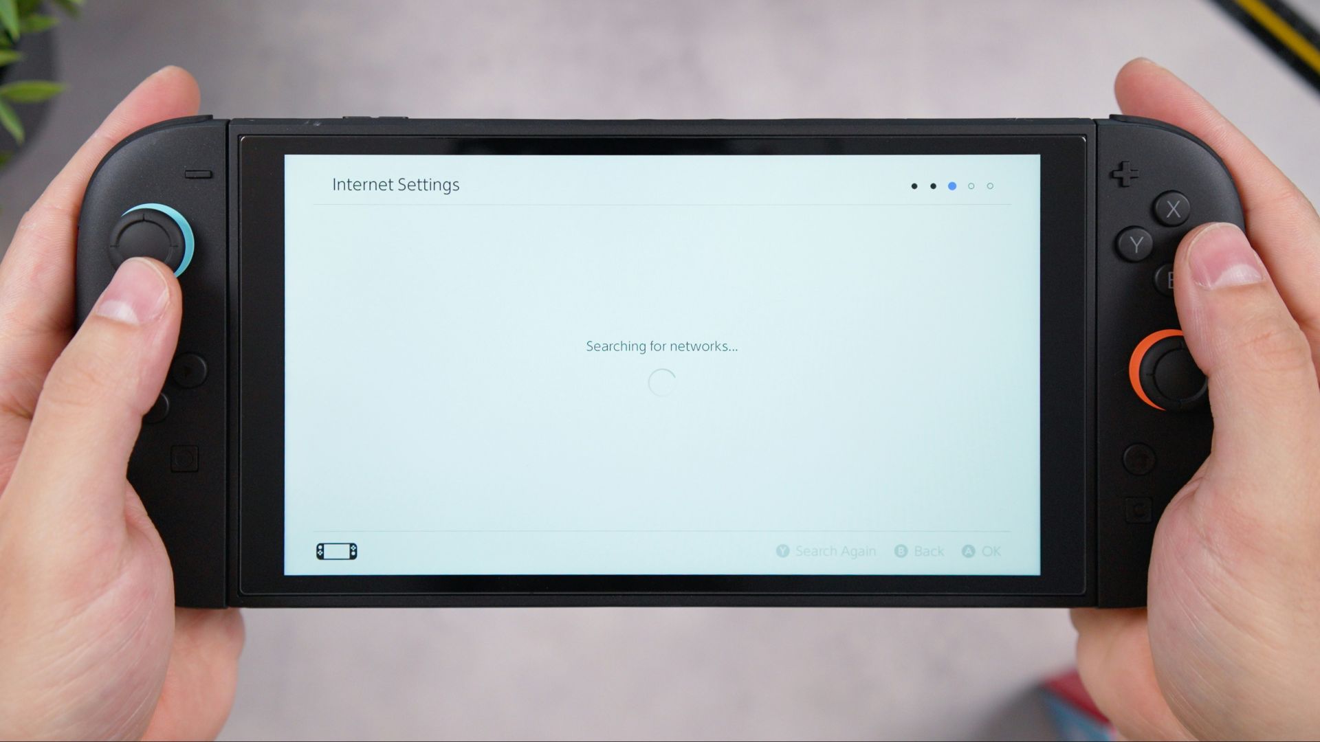 Hands hold a handheld gaming console.