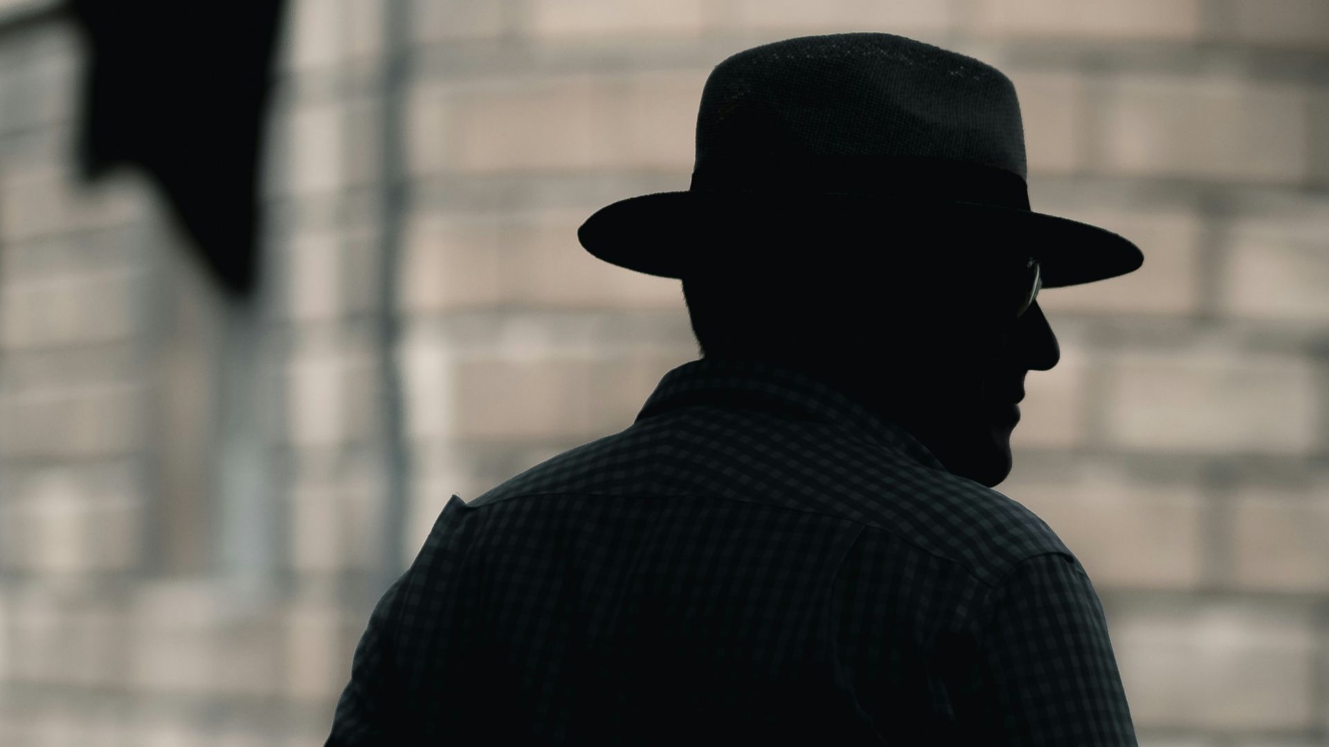 silhouette photo of a man with hat standing near concrete building at daytime