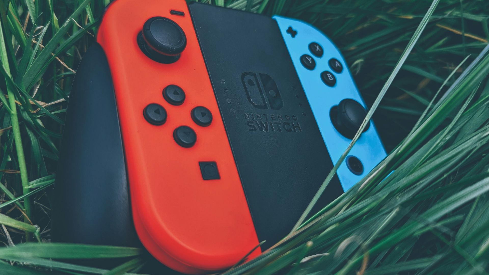 a red and black video game controller on grass