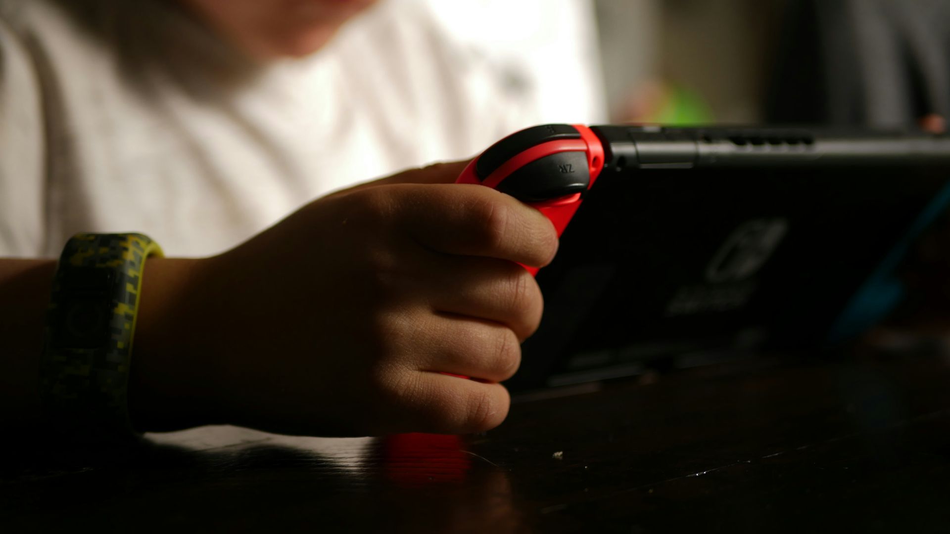 boy in white crew neck t-shirt holding black and red cordless device