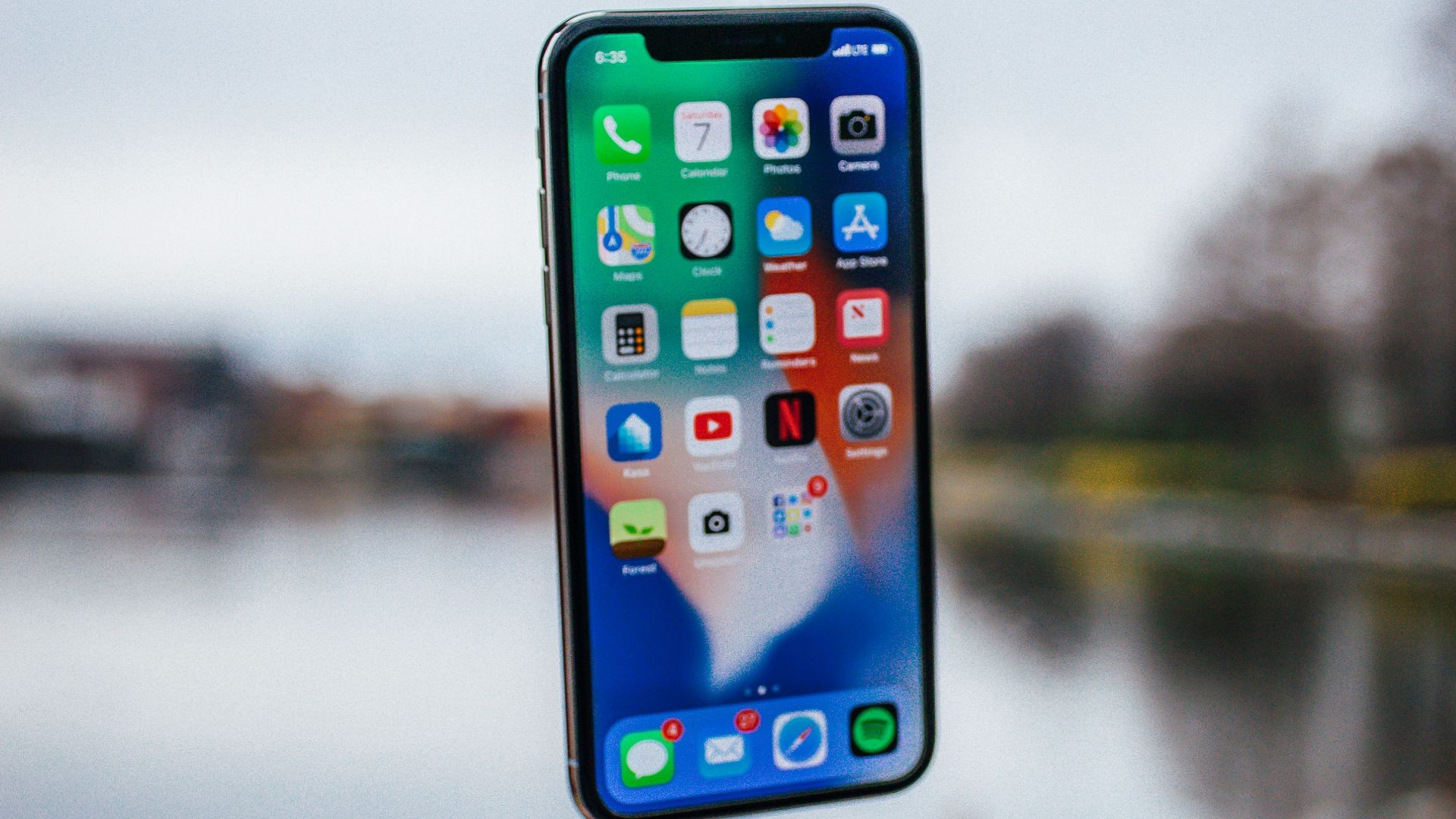 silver iPhone X floating over open palm