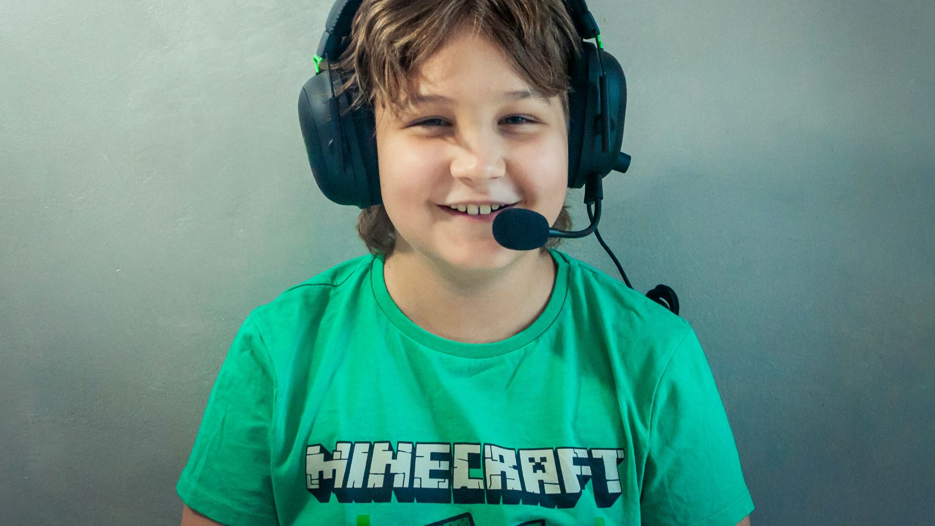A young boy wearing headphones and a green shirt