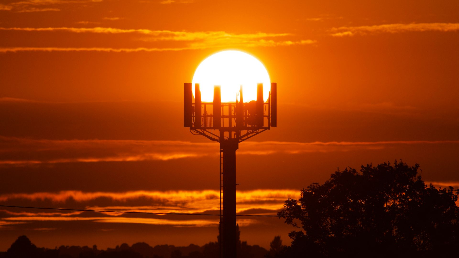 the sun is setting behind a tower with a cell phone on it