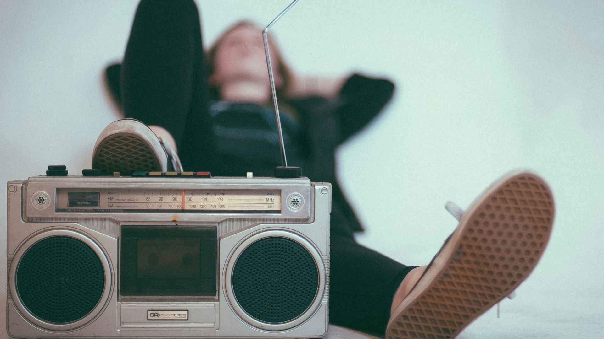 woman laying on bed near gray radio