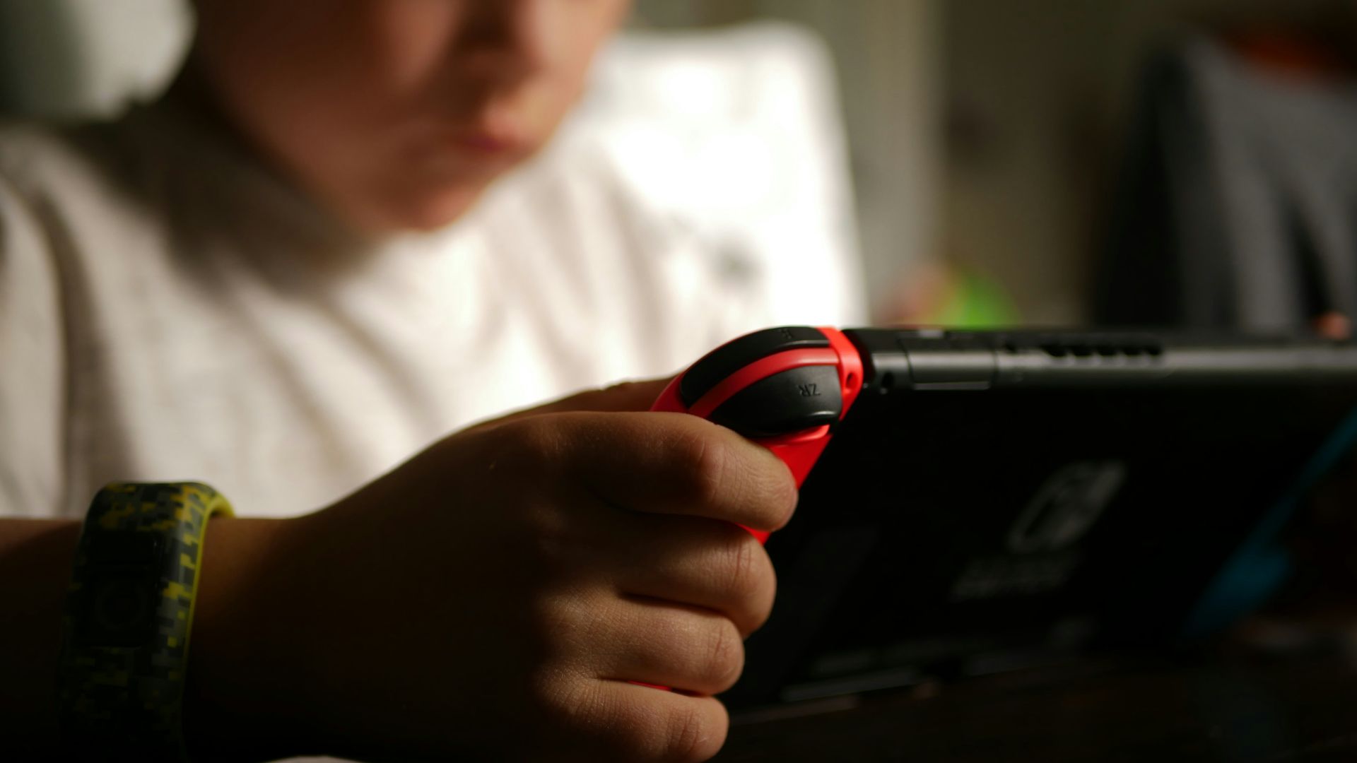 boy in white crew neck t-shirt holding black and red cordless device