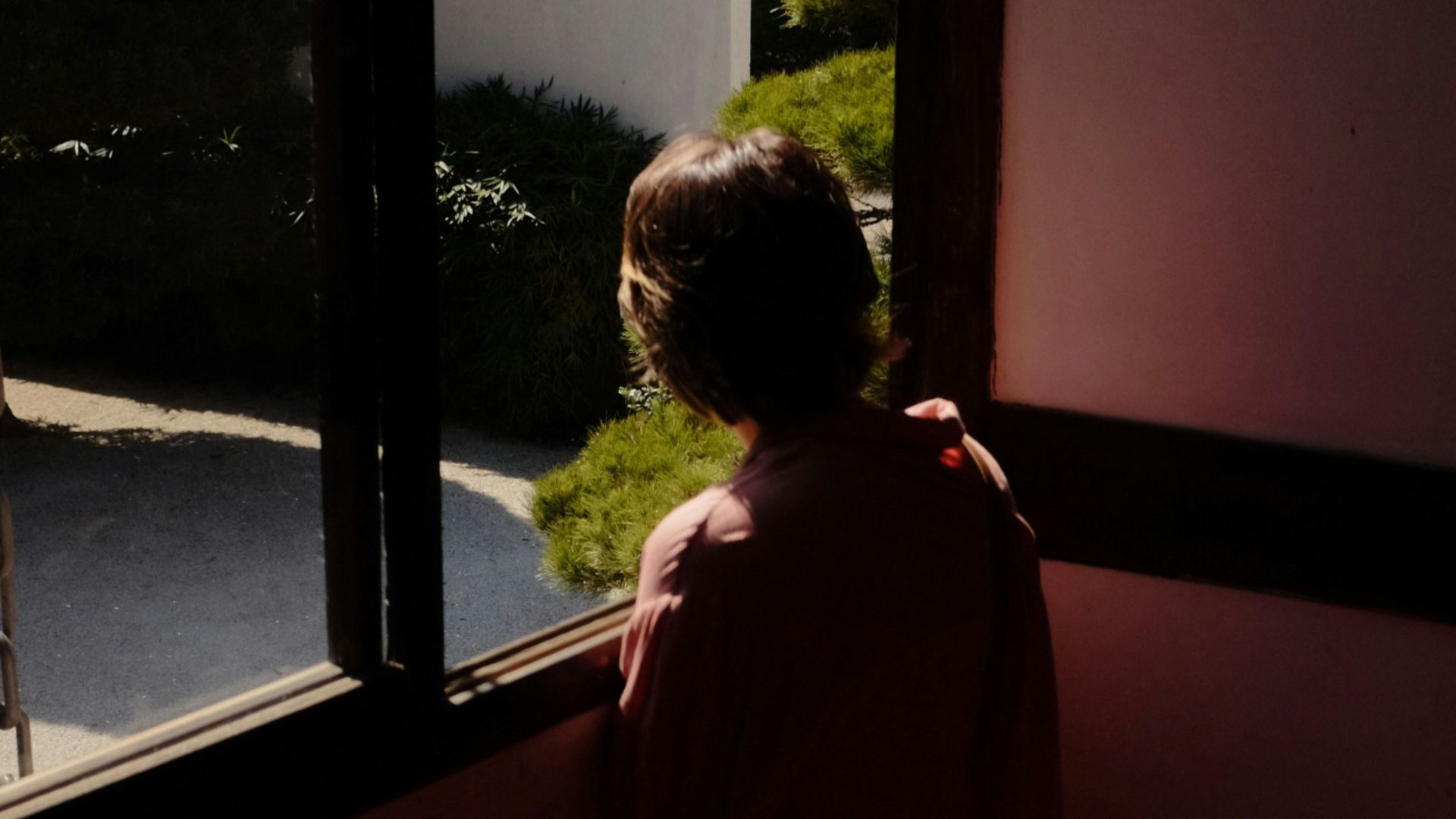 A woman standing in front of a window in a dark room
