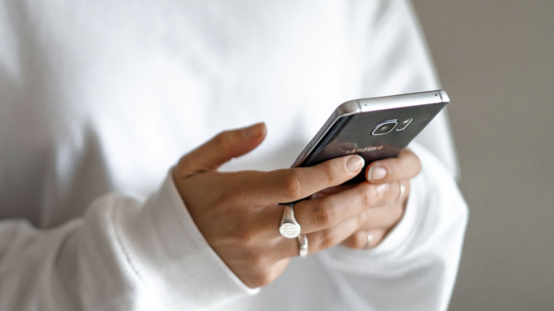 person in white long sleeve shirt holding black smartphone