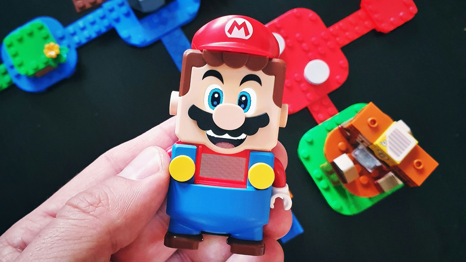 a hand is holding a toy of a mario