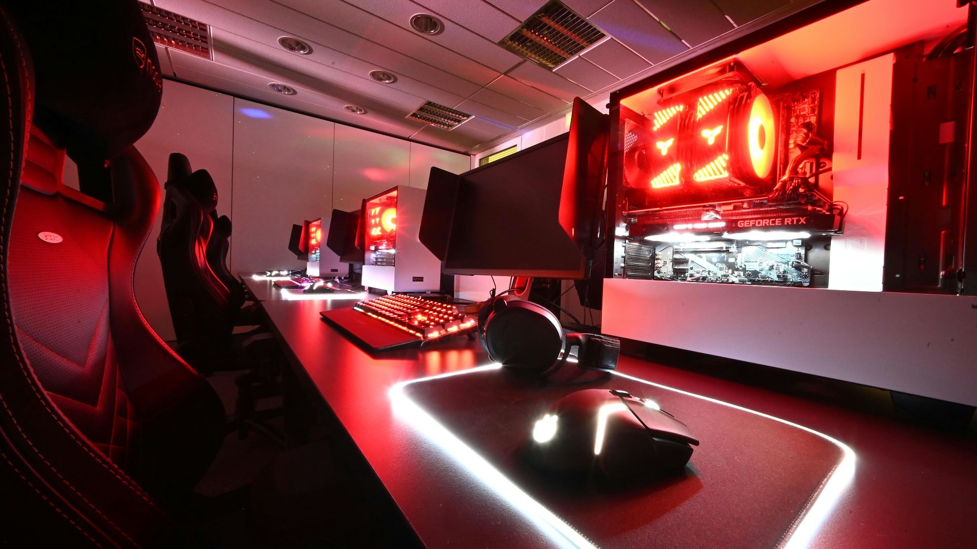 a gaming room with red lights and a large screen