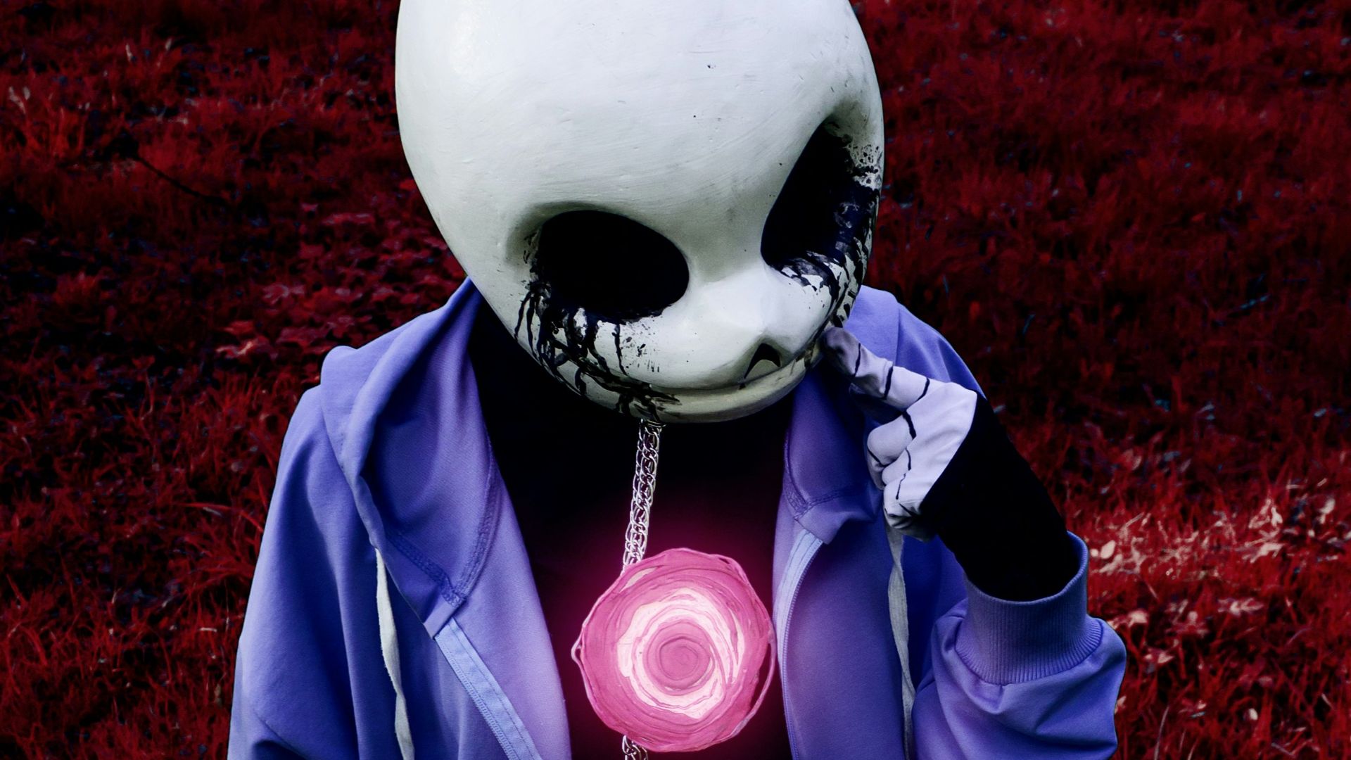 Person in a white mask and blue hoodie standing outdoors