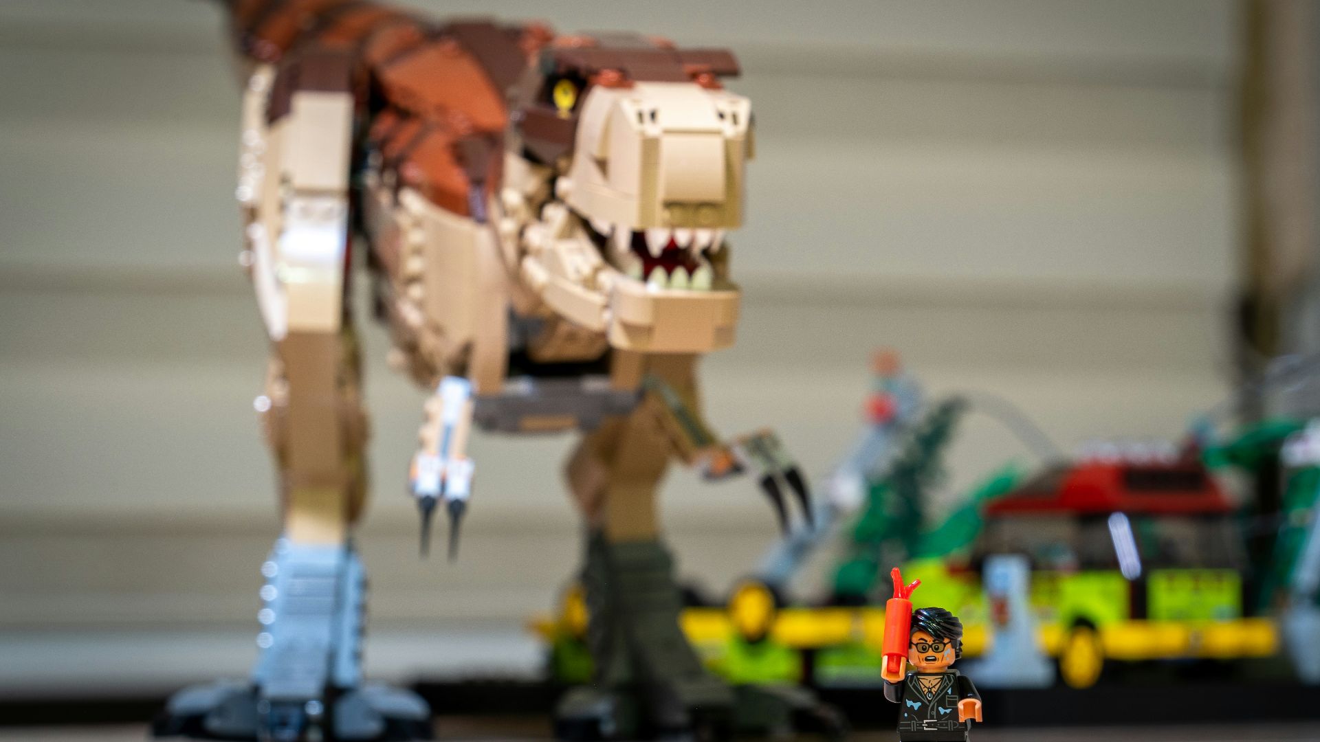 a lego dinosaur and a lego man in front of a building