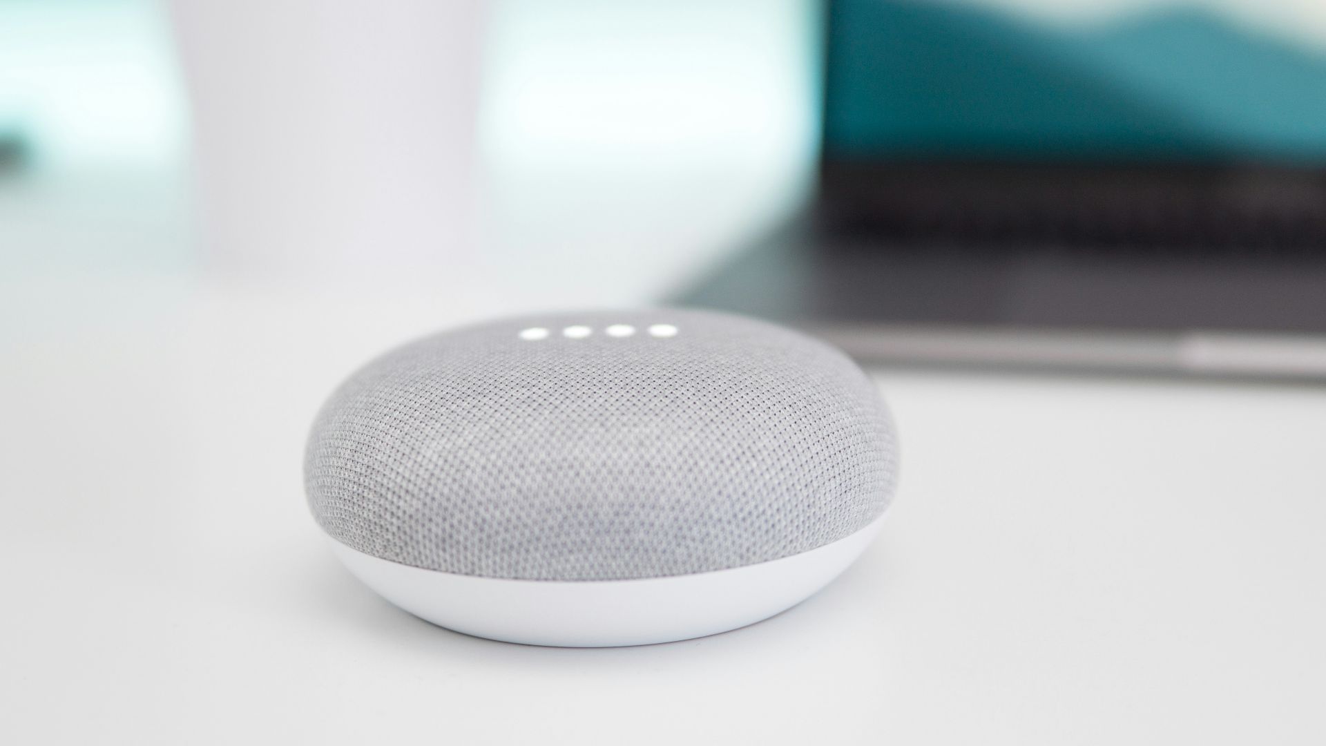 turned on gray and white Google Home Mini speaker on white surface