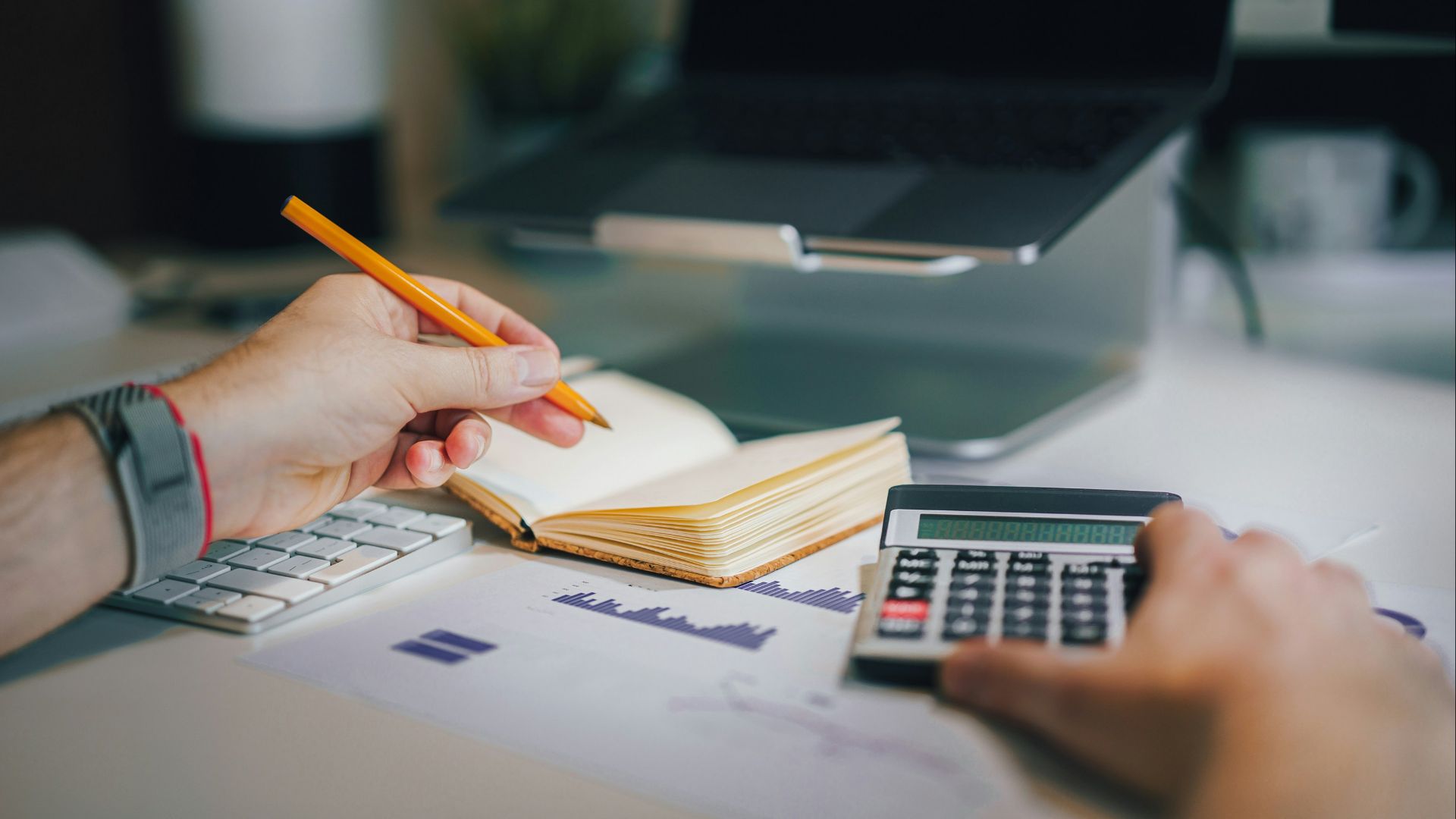 a person sitting at a desk with a calculator and a notebook