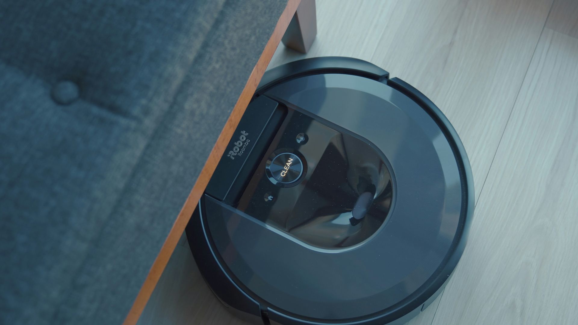 a robotic vacuum is on the floor next to a couch