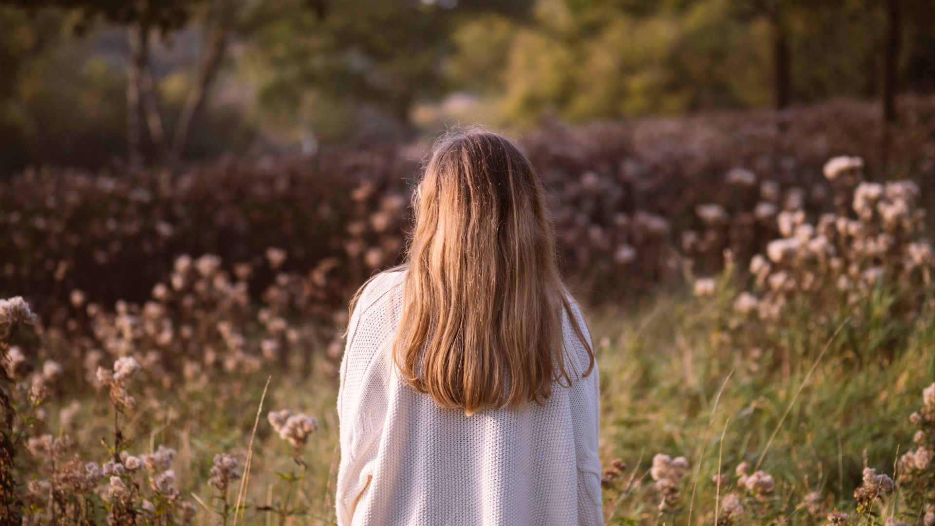 woman back surrounded by green and brown grass