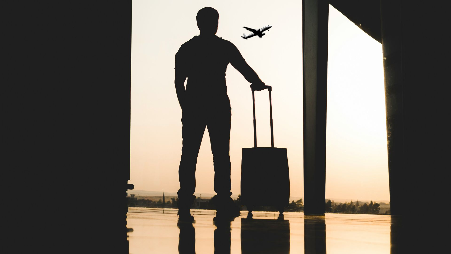 silhouette of man holding luggage inside airport