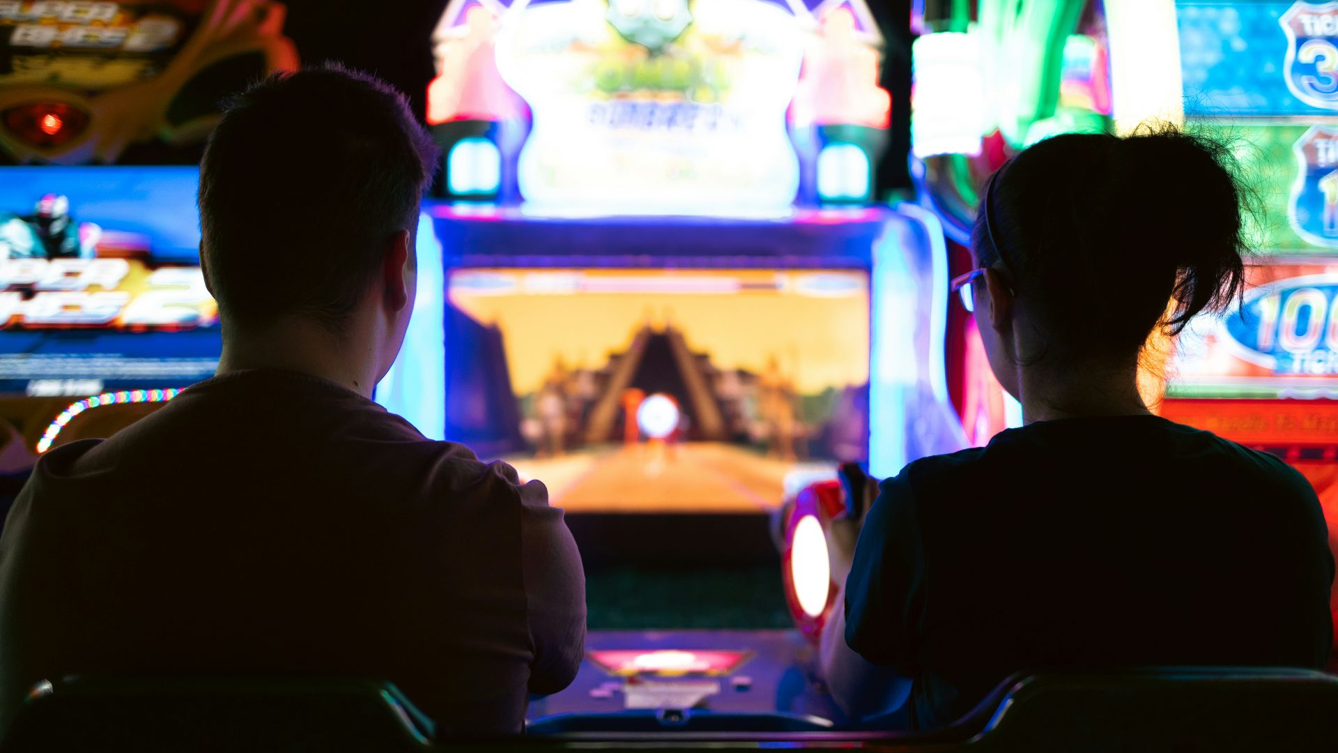 a couple of men sitting in a room with a large screen