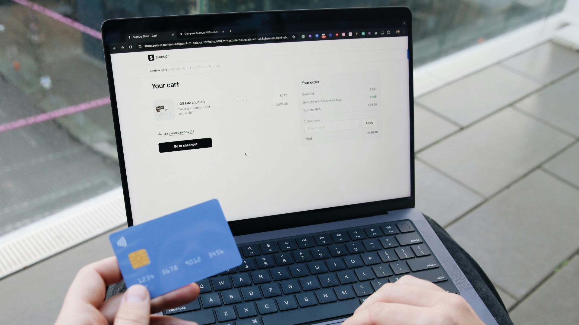 A person sitting in a chair with a laptop and a credit card