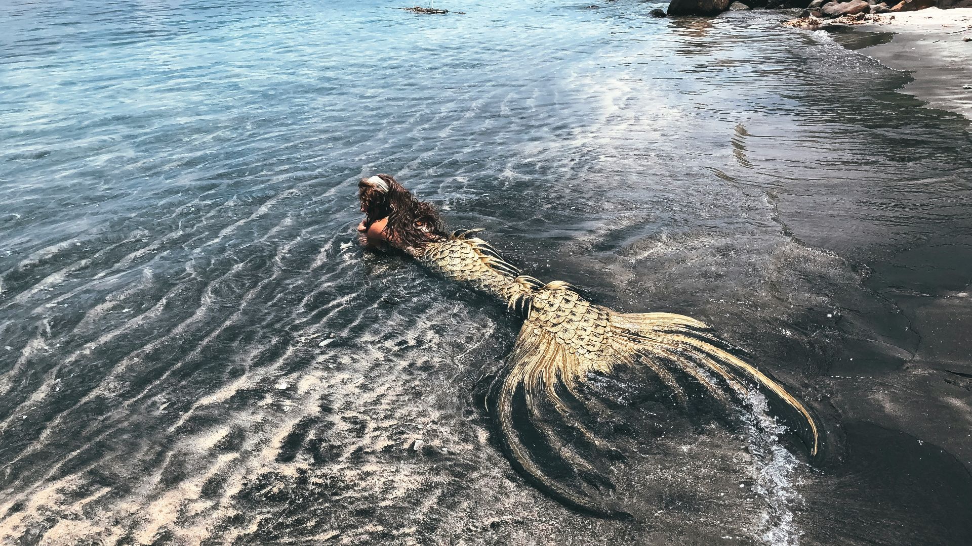 woman in black and white dress on brown rock formation on sea during daytime